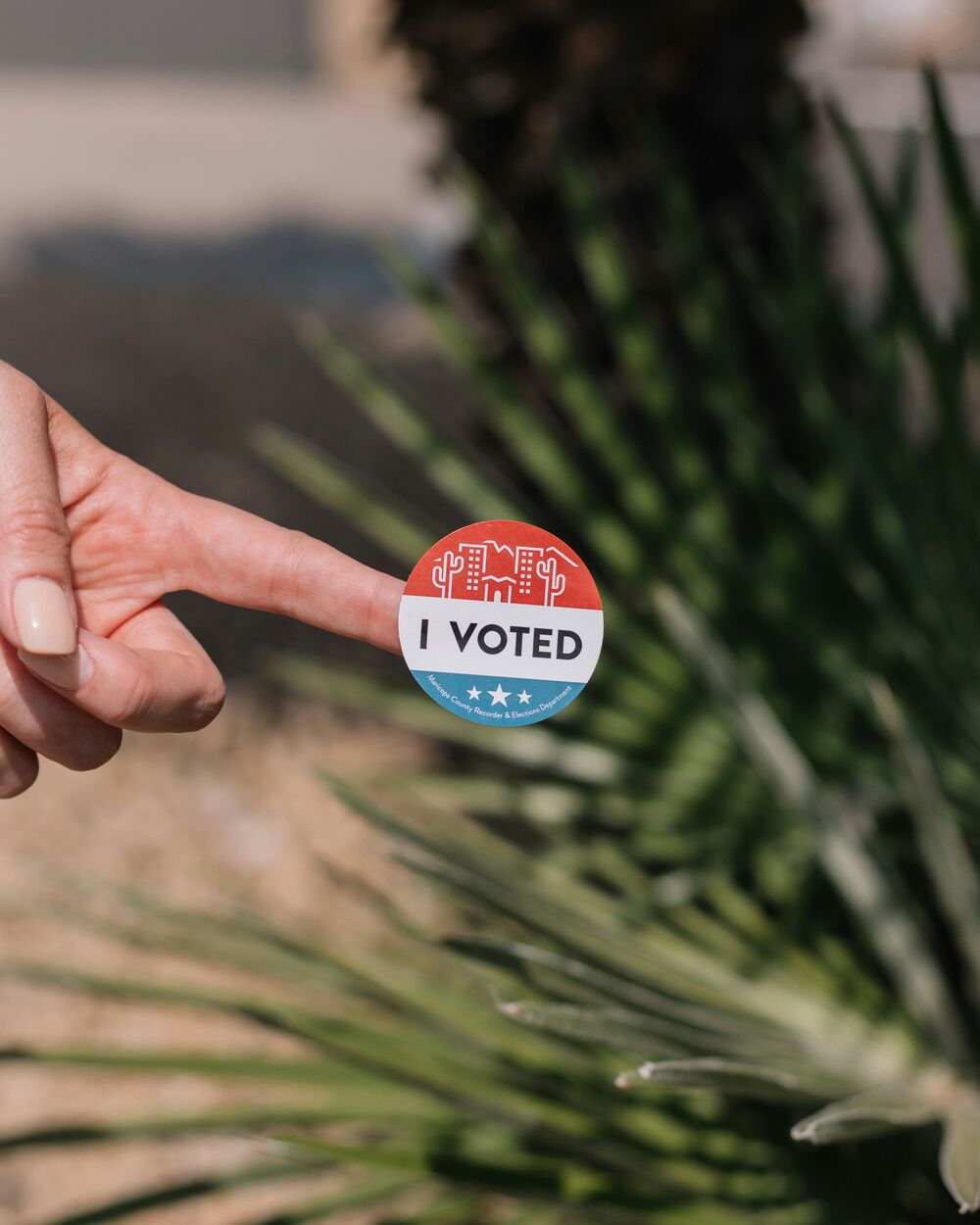 A hand holding an I Voted sticker